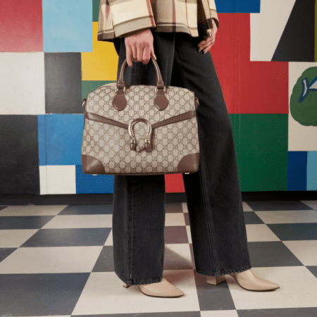 A girl stands with her lower half visible, holding a bag in her hand
