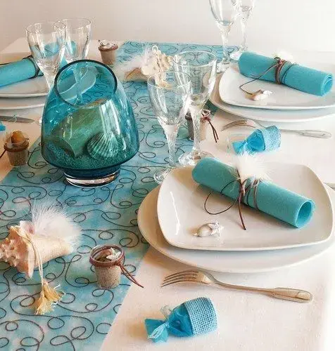 Table decor showcasing beach elements like seashells, starfish, and personalized name cards for a coastal dining experience