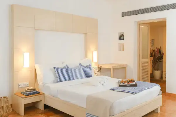 A luxurious coastal bedroom featuring white sheets, a plush duvet, decorative shams