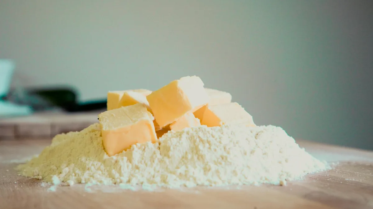 Cold unsalted butter cut into uniform cubes with fresh lemons on cutting board