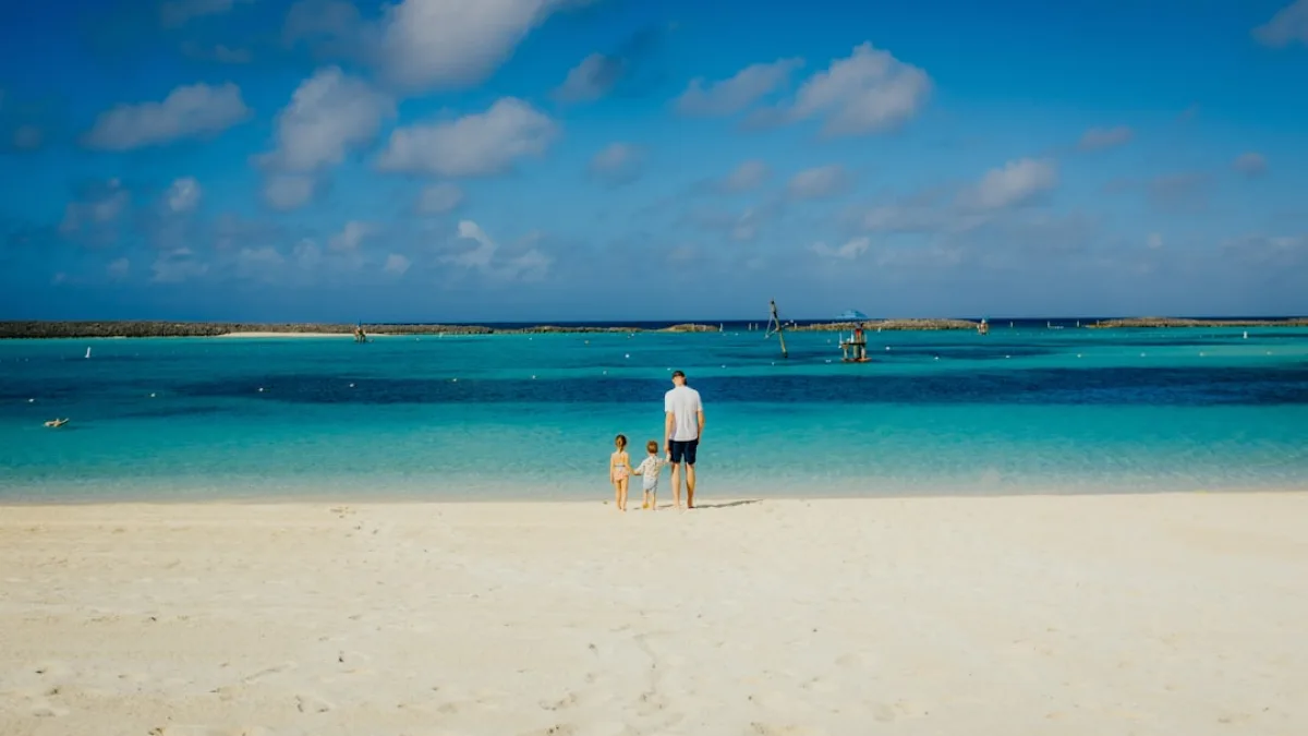 Family with children enjoying calm shallow beach waters at Hoopers Bay Exuma